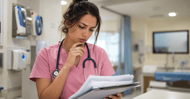 Doctora con uniforme quirúrgico rosa analizando un caso clínico para el EGEL Plus Medicina General